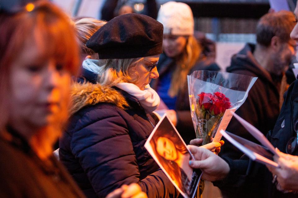 A mourner holding roses is handed a program and let in through the gates of Graceland for a public service celebrating the life of Lisa Marie Presley.