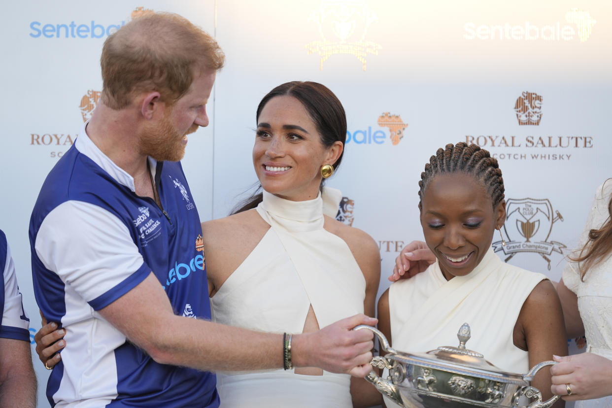 Meghan Markle, Harry y la Dr Sophie Chanduaka en la premiación del torneo Royal Salute Polo Challenge, llevado a cabo en Wellington, Florida, donde el príncipe jugó y ganó. (AP Photo/Rebecca Blackwell)