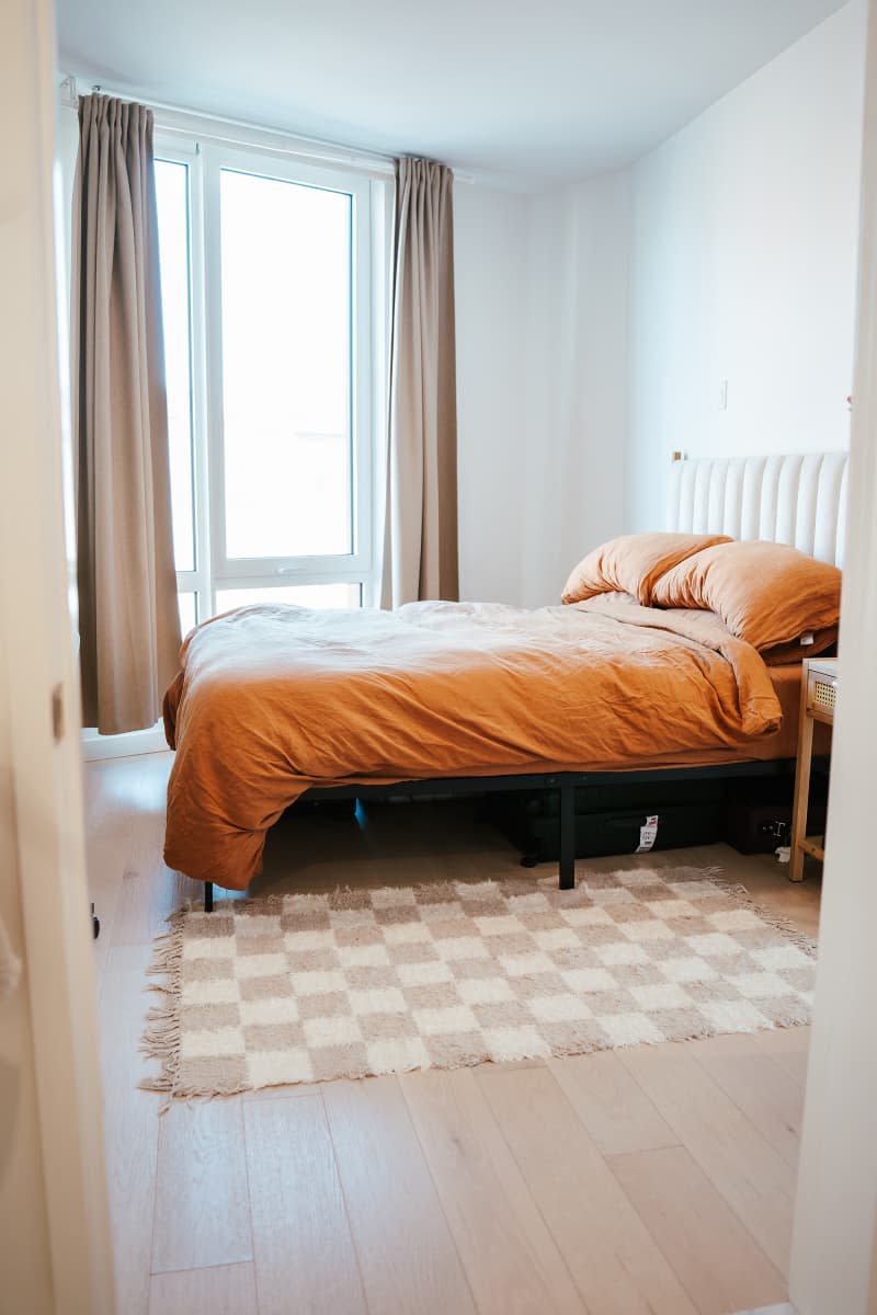 Checker board rug in bedroom with burnt orange bedding.