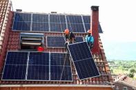 FILE PHOTO: Kauahou and Navarro, workers of the installation company Alromar, set up solar panels on the roof of a home in Colmenar Viejo