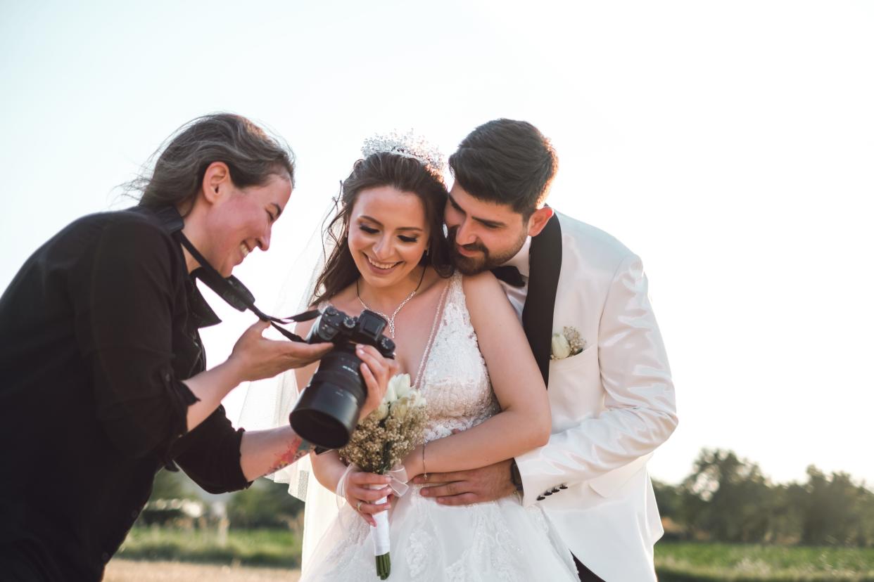 A photographer showing a bride and groom images on a camera.