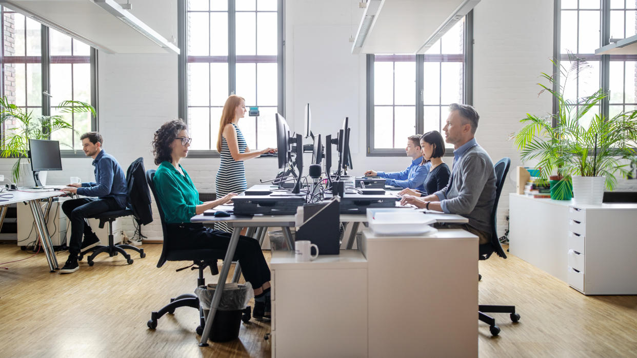 Business people at their desks in a busy, open plan office.