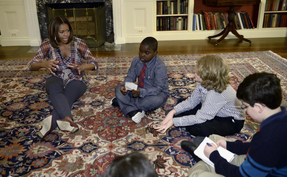 First lady Michelle Obama sits on the floor with "kid reporters," from second from left, Justin Creppy, 6, from Upper Marlboro, Md., Zachary Shannon, 10, from Garrison, N.Y., and Raphael Chambers, 13, from Reston, Va., right, Monday, April 21, 2014, in the Library of the White House in Washington. (AP Photo/Susan Walsh)