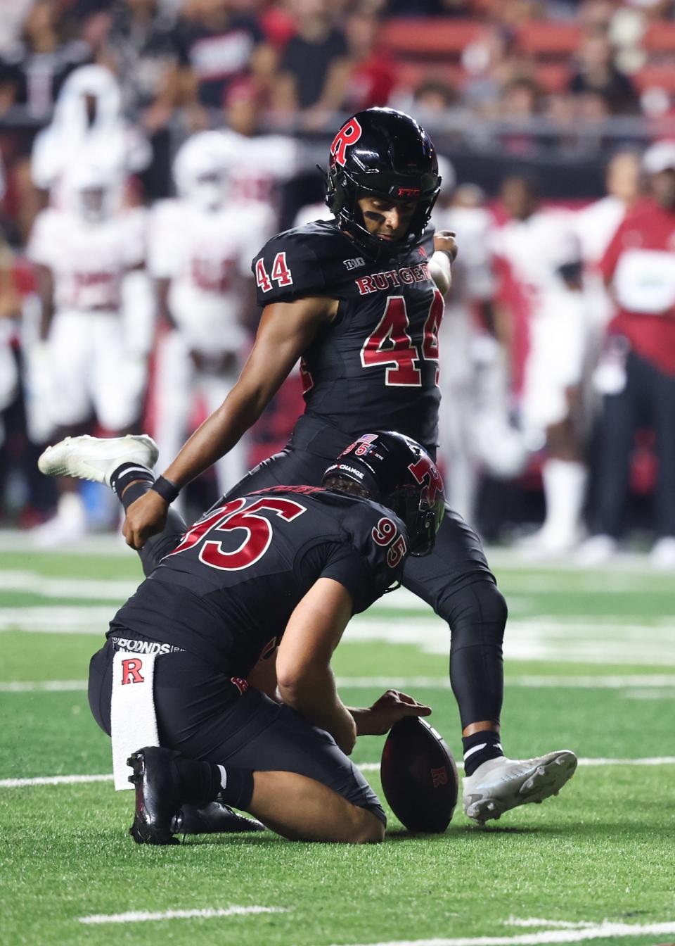 Rutgers Scarlet Knights placekicker Jai Patel (44) kicks an extra point as punter Flynn Appleby (95) holds