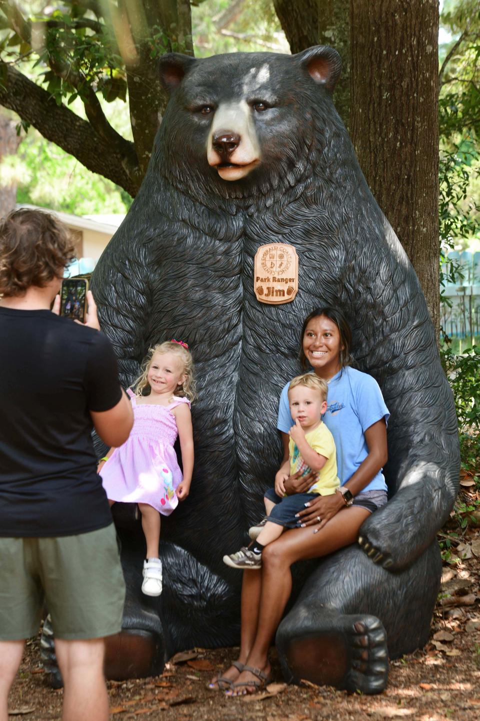 Ana Reynolds, right, poses with nephew Jonah Benner and niece Macie Benner atop a giant Florida black bear at the Emerald Coast Science Center. The bear is part of the science center's new Florida National Scenic Trail mural and exhibit.