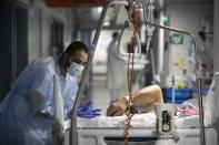 A medical staff member speaks with a COVID-19 patient in the infectious disease ward of the Strasbourg University Hospital, eastern France, Thursday Jan. 13, 2022. The omicron variant is exposing weaknesses at the heart of Europe's public health system. In France and Britain, a sharp rise in coronavirus hospitalizations coupled with staff falling sick has led to a shortage of beds. (AP Photo/Jean-Francois Badias)