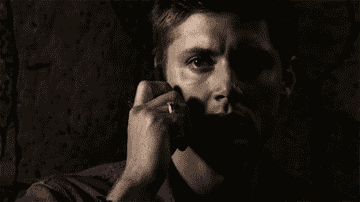 Dean from Supernatural holding a phone to his hear and looking scared