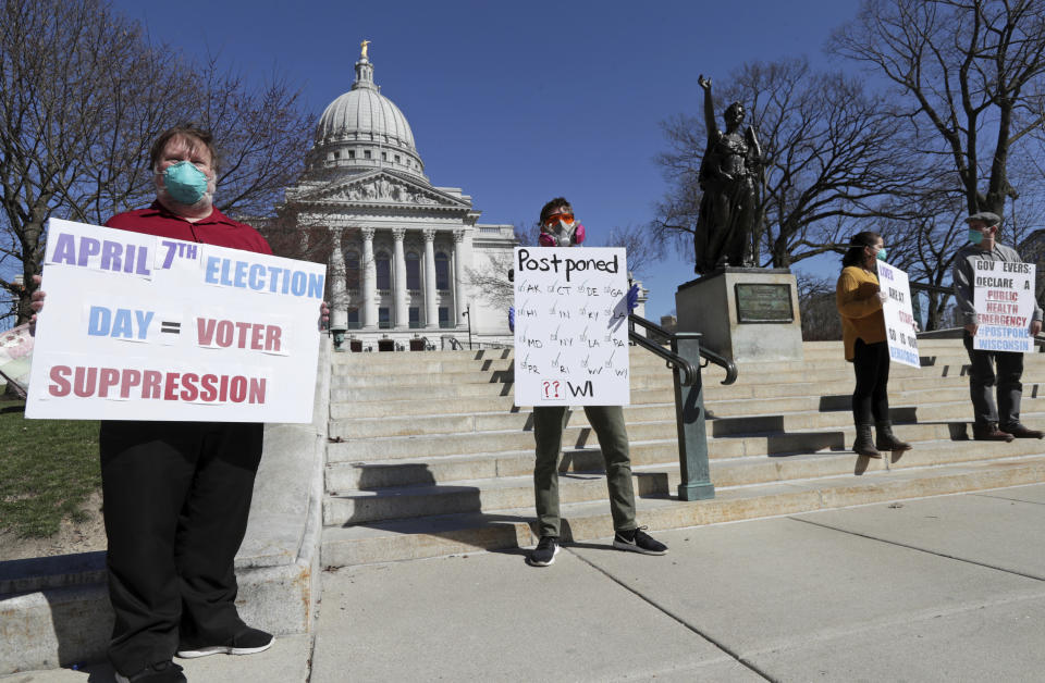 A group with C.O.V.I.D., Citizens Outraged Voters in Danger, including, from left, Ron Rosenberry Chase and Jim O'Donnell, protest while wearing masks outside the State Capitol during a special session regarding the spring election in Madison, Wis., Saturday, April 4, 2020. (Amber Arnold/Wisconsin State Journal via AP)