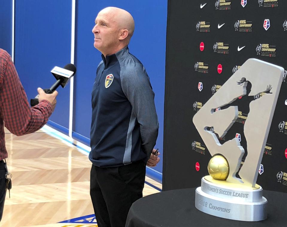 FILE - In this Sept. 20, 2018, file photo, North Carolina Courage coach Paul Riley is interviewed by a reporter next to the trophy for the National Women's Soccer League championship during a media event at Nike in Beaverton, Ore. The National Women’s Soccer League will not play the games scheduled for this weekend as it deals with the fallout from allegations of sexual misconduct against a former coach. North Carolina Courage coach Paul Riley was fired by the team following a report in The Athletic that detailed the alleged misconduct, which included claims from two former players of sexual coercion. The NWSL did not specify Friday, Oct. 1, 2021, whether the games were canceled or postponed. (AP Photo/Anne M. Peterson, File)
