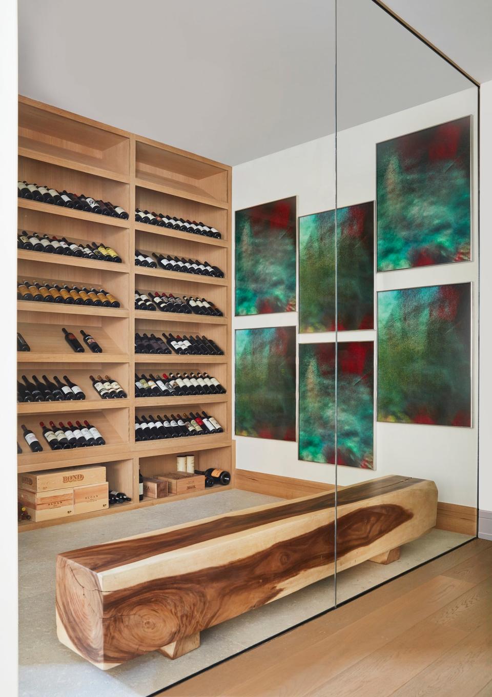 The wine cellar came with the home, which was designed by Pacific Peninsula Architecture. “The architect provided us with such great bones to work with,” says Legaspi. The artwork on the wall is Double Jicky by Eileen Quinlan, and the wood bench is from Lau’s existing collection.