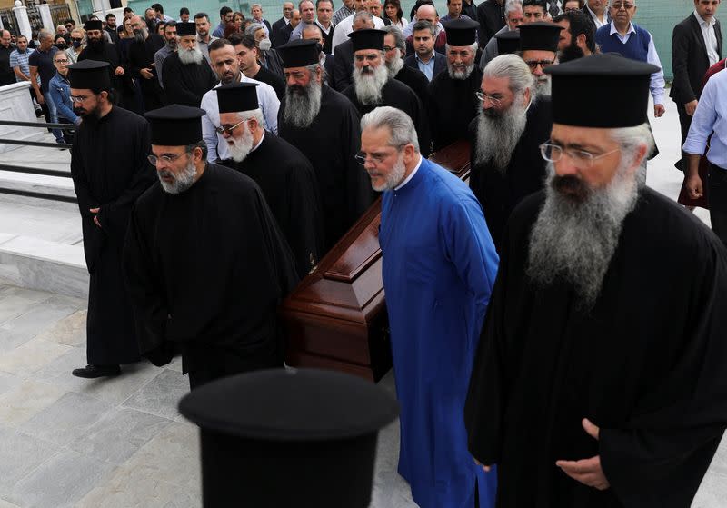 Greek Orthodox priests carry the coffin of the late Archbishop Chrysostomos II outside the Apostle Varnavas Cathedral, in Nicosia