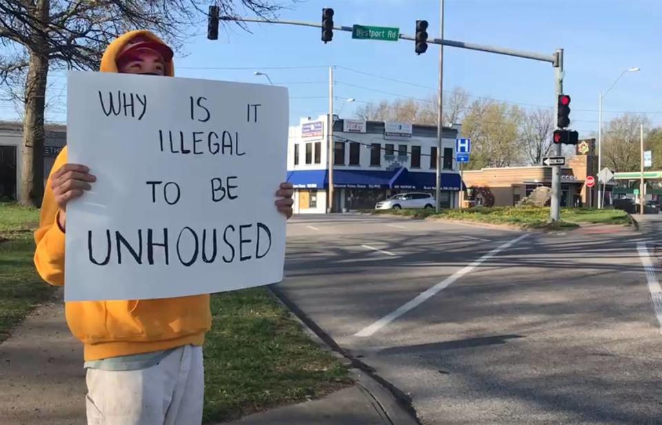 Outside of Camp 6ixx, a homeless encampment at Westport Road and Southwest Trafficway, a man holds a sign in support of those without housing.