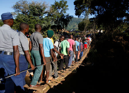 FILE PHOTO: Survivors of cyclone Idai cross a temporary foot bridge to receive aid in Chipinge, Zimbabwe, March 25, 2019. REUTERS/Philimon Bulawayo/File Photo