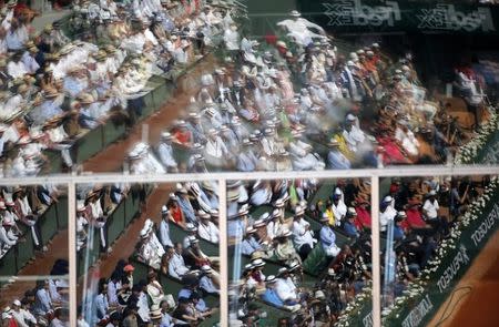 Spectators are reflected in a window as they watch the men's singles final match between Novak Djokovic of Serbia and Stan Wawrinka of Switzerland at the French Open tennis tournament at the Roland Garros stadium in Paris, France, June 7, 2015. REUTERS/Jean-Paul Pelissier