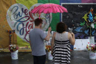 <p>Dalton Hoffine and Nicole Stark (L-R) visit the memorial to the victims of the mass shooting setup around the Pulse gay nightclub one day before the one year anniversary of the shooting on June 11, 2017 in Orlando, Florida. (Joe Raedle/Getty Images) </p>