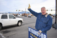 Republican U.S. House candidate Ryan Zinke waves to drivers passing at an intersection, Oct. 27, 2022, in Bozeman, Mont. The former interior secretary under Trump stood in the cold outside a Loaf 'N Jug gas station and weathered a barrage of curses, friendly honks, obscene gestures and shouts of support. (AP Photo/Matthew Brown)
