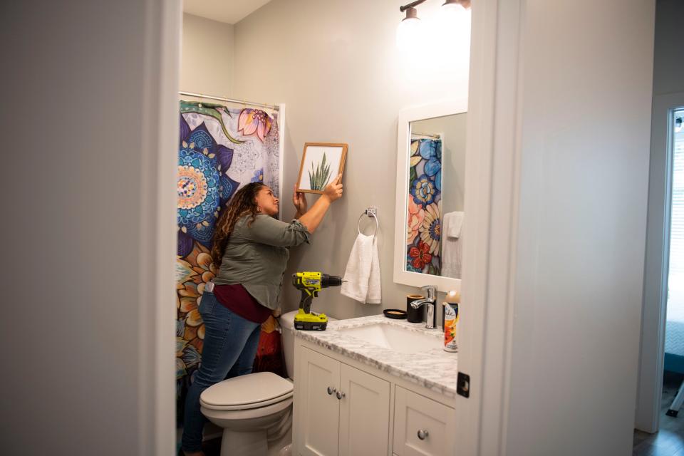 Alycia Cilli, 24, hangs art in the bathroom while redesigning one of four properties she rents and subleases on Air Bnb in Greenville on Thursday, August 19, 2022. 