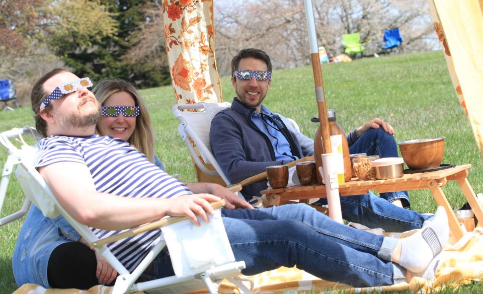 Nick Moulakais, right, of Granville, Emmily Morris, of Newark, and Benjamin Morrison, of Newark, view the solar eclipse at The Dawes Arboretum on Monday, April 8, 2024.