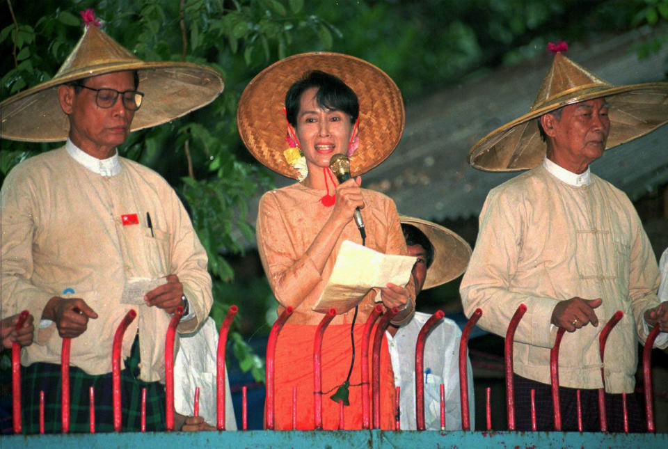 FILE - In this June 16, 1996, file photo, pro-democracy leader Aung San Suu Kyi, center, under house arrest speaks to supporters outside her home as senior leaders in the National League for Democracy Tin Oo, left, and U Kyi Maung listen, in Yangon, Myanmar. Suu Kyi was ousted in the Feb. 1, 2021 coup. As arrests of dissidents continue during anti-coup protests across Myanmar, experts are concerned that a new generation of political prisoners will begin to fill the country’s prisons. (AP Photo/Stuart Isett, File)