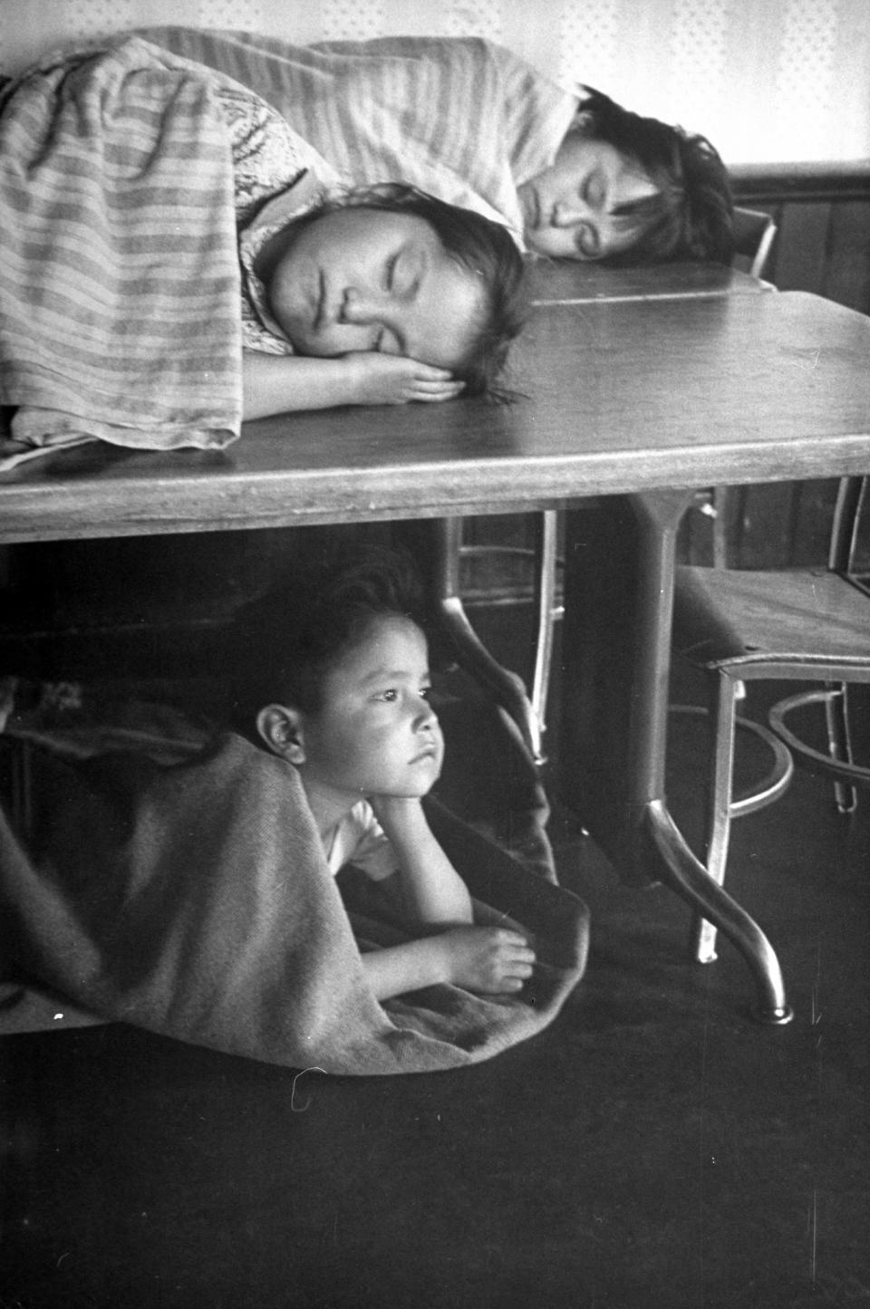 Navajo children taking naps on the tables and the floor.
