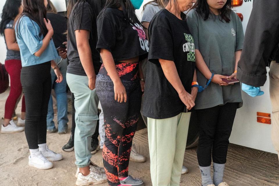 PHOTO: Migrants get handcuffed as a pair before getting onboard a bus to be transported after crossing the border into the U.S. from Mexico in Jacumba Hot Springs, Calif., Nov. 11, 2023. (Go Nakamura/Reuters)