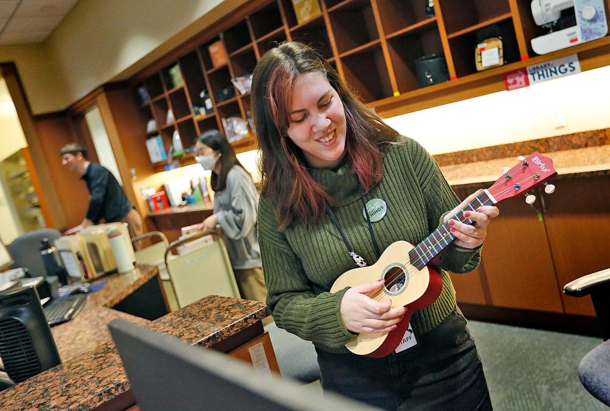 Library assistant Autumn Nutile strums a ukulele that can be borrowed from the Library of Things at the Thomas Crane Public Library in Quincy on Wednesday, Jan. 31, 2024.