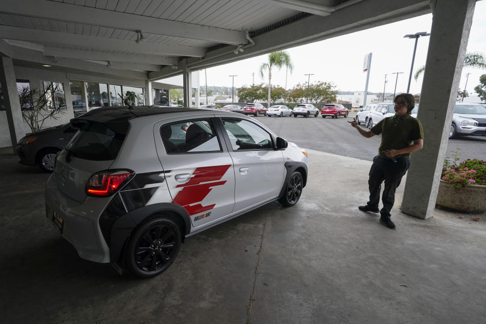 Mitsubishi sales person Matthew Boston points to a new Mitsubishi Mirage for sale at El Cajon Mitsubishi Tuesday, Aug. 8, 2023, in El Cajon, Calif. At a time when auto buyers increasingly want pricey SUVs and trucks and fewer want small cars, the Mirage remains the lone new vehicle whose average sale price is under 20 grand — a figure that once marked a kind of unofficial threshold of affordability. (AP Photo/Gregory Bull)