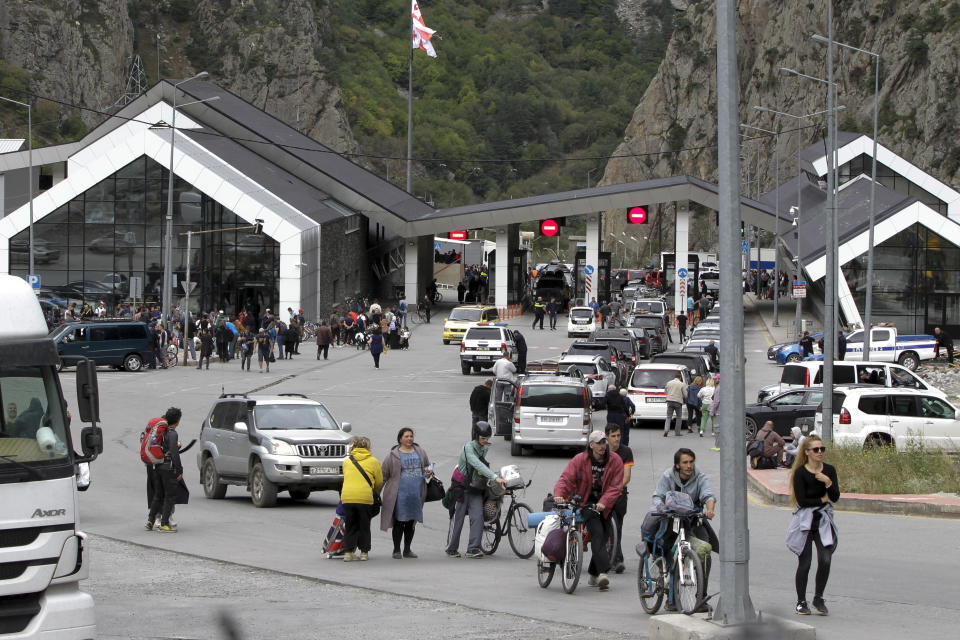 People, most of them Russians, walk after they crossed the border between Georgia and Russia at Verkhny Lars, in Georgia, Wednesday, Sept. 28, 2022. Protesters come from Tbilisi to voice their concerns over the exodus of Russian citizens into Georgia that has increased since Vladimir Putin announced partial mobilization. (AP Photo/Shakh Aivazov)