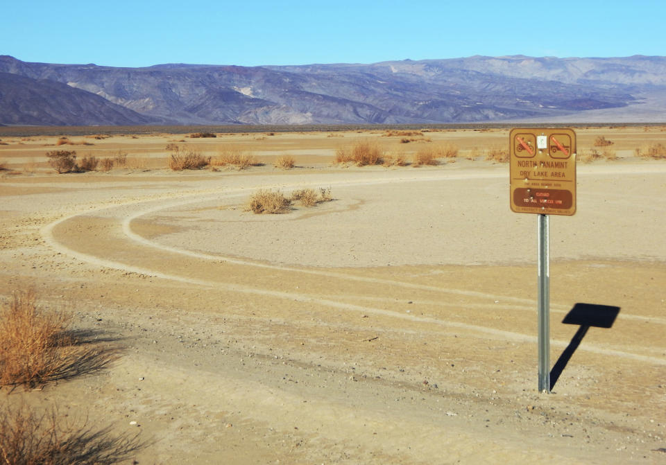 This undated photo provided by the U.S. National Park Service shows vehicle tracks beyond a sign banning vehicles in the North Panamint dry lake area during the recent federal government shutdown in an area of Death Valley National Park, Calif. National parks across the United States are scrambling to clean up and repair damage caused by visitors and storms during the government shutdown while bracing for another possible closure ahead of the usually busy President's Day weekend. (National Park Service via AP)