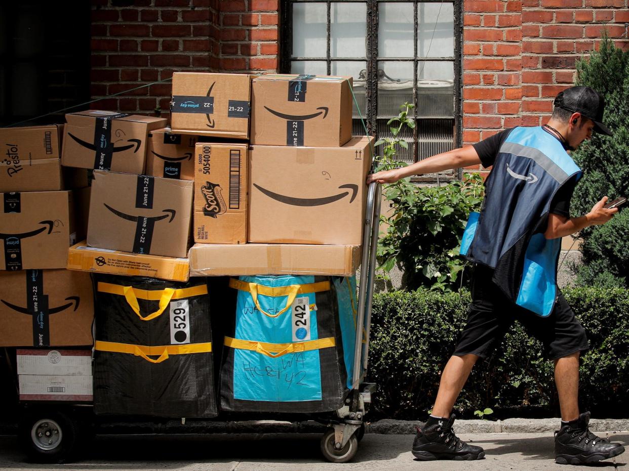 An Amazon delivery worker pulls a delivery cart full of packages during its annual Prime Day promotion in New York