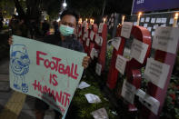 A man holds a poster during a candle light vigil for the victims of Saturday's soccer riots, outside the Youth and Sports Ministry in Jakarta, Indonesia, Sunday, Oct. 2, 2022. Panic and a chaotic run for exits after police fired tear gas at an Indonesian soccer match in East Java to drive away fans upset with their team's loss left a large number of people dead, most of whom were trampled upon or suffocated. (AP Photo/Dita Alangkara)