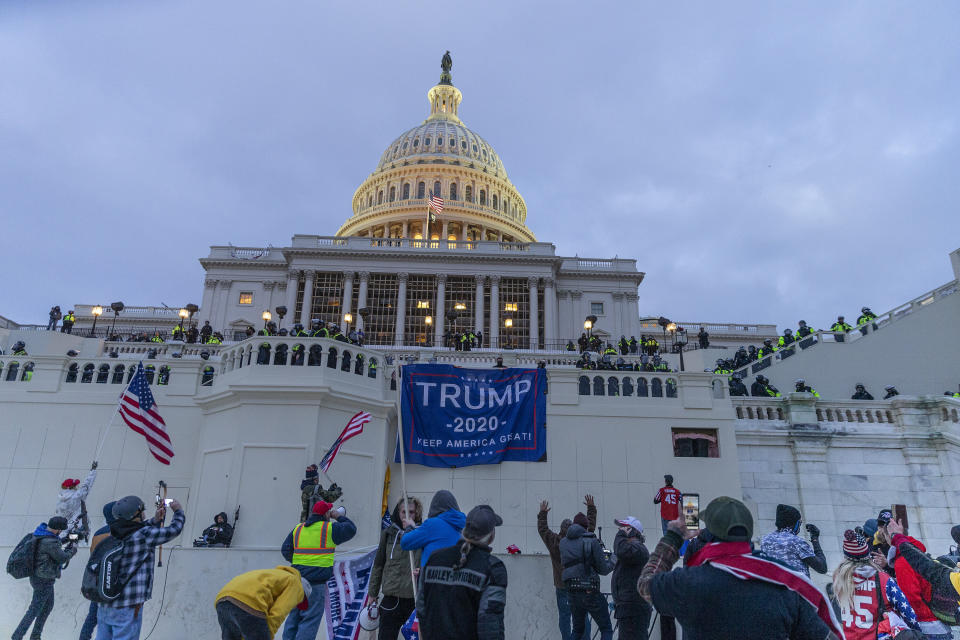 Insurrectionists hang Trump 2020 flags on the Capitol as they run rampant the building. (Photo: Lev Radin/Pacific Press/LightRocket via Getty Images)