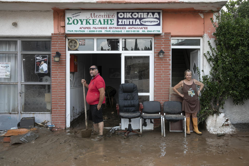 Locals try to move away water and mud from their shop following a storm at the village of Politika, on Evia island, northeast of Athens, on Sunday, Aug. 9, 2020. Five people have been found dead and dozens have been trapped in their homes and cars from a storm that has hit the island of Evia, in central Greece, police say. (AP Photo/Yorgos Karahalis)