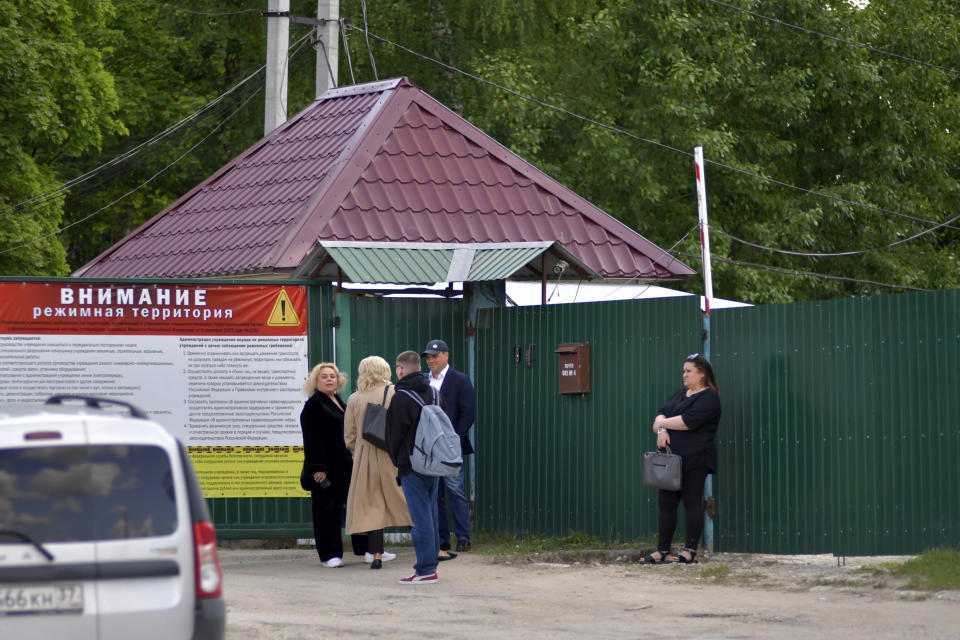 Russian opposition leader Alexei Navalny's lawyers Olga Mikhailova, center left back to camera, and Vadim Kobzev, center, talk to each other as they wait to enter the colony to attend a court hearing in Melekhovo, Russia, Tuesday, June 6, 2023. A preliminary hearing will take place in a new case against opposition figure Alexei Navalny at a prison where he is held. (AP Photo)