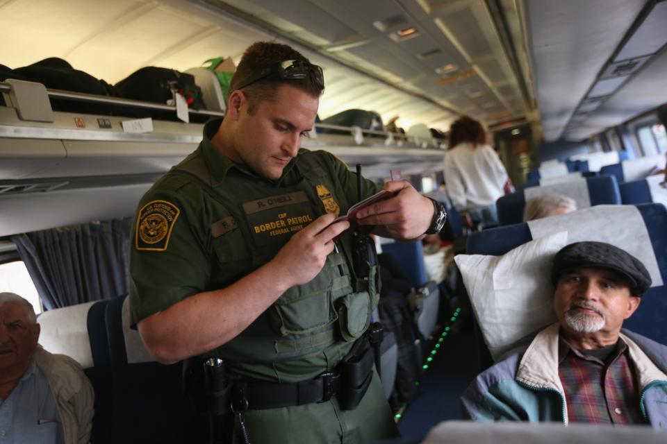 A U.S. Border Patrol agent checks passenger identifications aboard an Amtrak train from Chicago to New York City on June 5, 2013 in Depew, New York. The Border Patrol also monitors cross along the northern border between the United States and Canada. (Photo by John Moore/Getty Images)