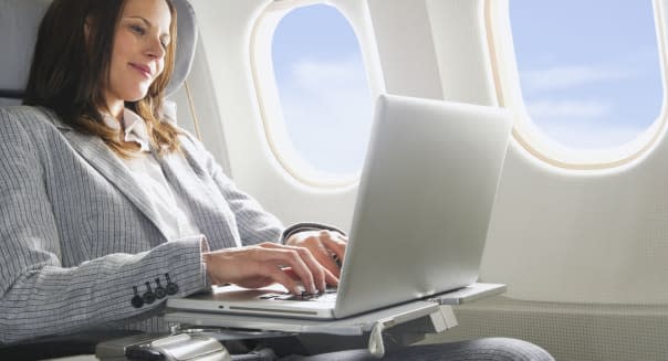 Germany, Bavaria, Munich, Mid adult businesswoman using laptop in business class airplane cabin