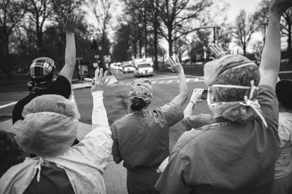 Image: Health care workers from Westchester Medical Center wave and cheer as first responders pass by in a caravan of lights and sirens in Valhalla, N.Y., on April 14, 2020. (John Moore / Getty Images file)