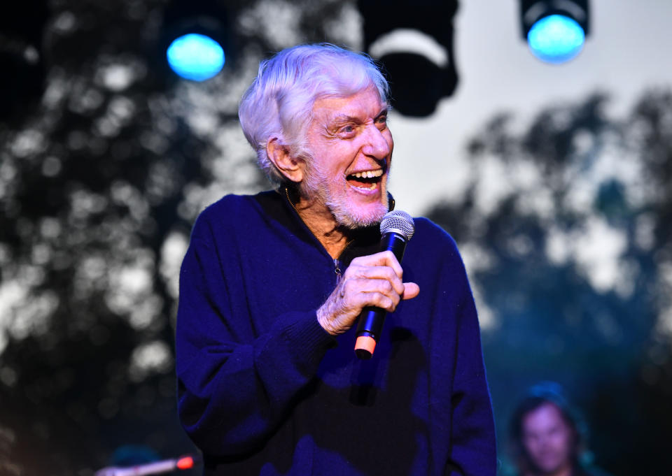 Dick Van Dyke smiles while holding microphone