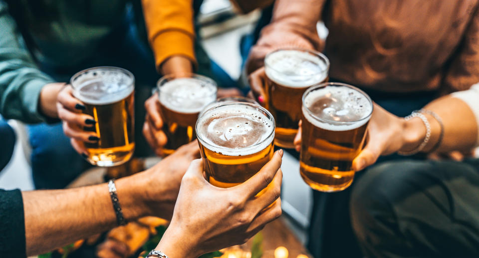 Numerous hands cheers while holding full glasses of beer.