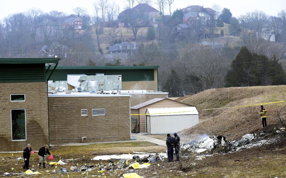 Investigators examine the site of a plane crash Tuesday, Feb. 4, 2014 near Nashville. The small plane crashed on Monday, near a YMCA in suburban Nashville, killing everyone on board and damaging cars in the parking lot. (AP Photo/Mark Zaleski)