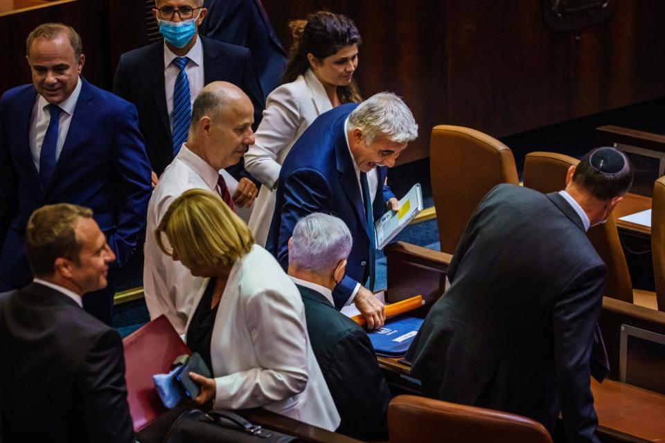 Lawmakers gather around a seated Benjamin Netayahu
