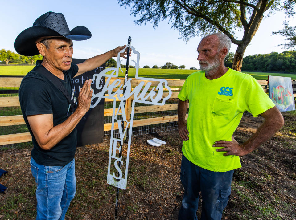 Roberto Marquez, wearing hat, talks with Brian Reinhardt.