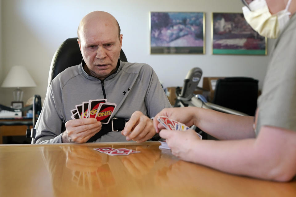 Former Detroit Red Wings star Vladimir Konstantinov plays Uno with health care provider Angela Martin, Tuesday, May 17, 2022, in West Bloomfield, Mich. Konstantinov is in danger of losing the 24/7 care he has had for two-plus decades. The disabled former NHL defenseman is a casualty of changes to Michigan's auto insurance law that curbed or cut what hospitals, residential care facilities and home providers can charge car insurers for care. Konstantinov suffered a severe brain stem injury from an accident in a limousine with an impaired driver after a Stanley Cup celebration nearly 25 years ago. (AP Photo/Carlos Osorio)