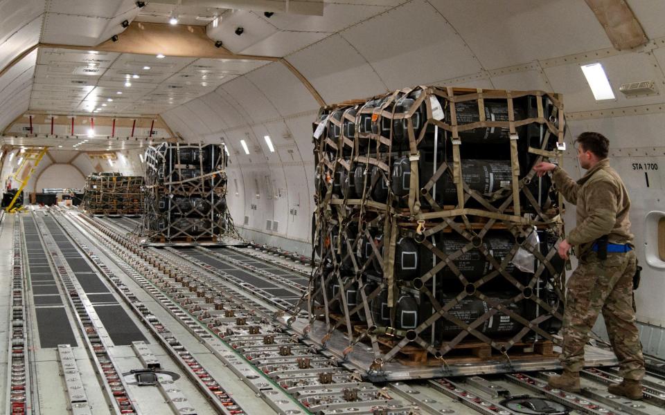 Senior Airman Cameron Manson inspects cargo netting on palletised ammunition, weapons and other equipment bound for Ukraine - U.S. Air Force photo/Roland Balik/Handout via REUTERS