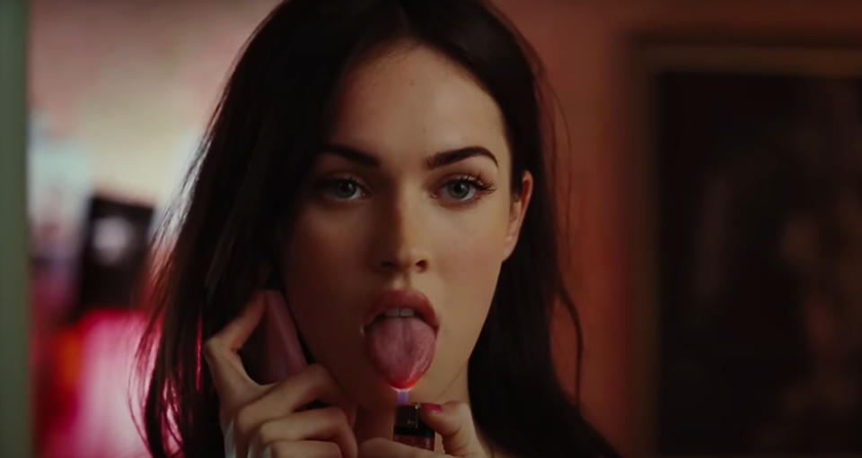 Megan Fox as Jennifer Check holds a phone to her ear and sticks out her tongue, touching it with a lighter flame.