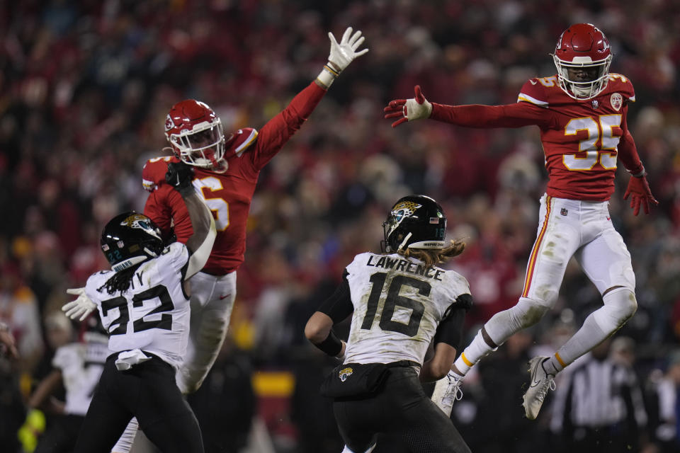 Jacksonville Jaguars quarterback Trevor Lawrence (16) works under pressure by Kansas City Chiefs safety Bryan Cook (6) and Kansas City Chiefs cornerback Jaylen Watson (35) during the second half of an NFL divisional round playoff football game, Saturday, Jan. 21, 2023, in Kansas City, Mo. The Kansas City Chiefs won 27-20. (AP Photo/Jeff Roberson)