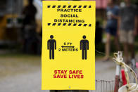 A sign encouraging social distancing is seen during the "World's Longest Yard Sale," Sunday, Aug. 9, 2020, in Dunlap, Tenn. The six-state yard sale, which was held despite concerns over the coronavirus pandemic, started Thursday and ended Sunday, and stretched from Alabama to Michigan. (C.B. Schmelter/Chattanooga Times Free Press via AP)