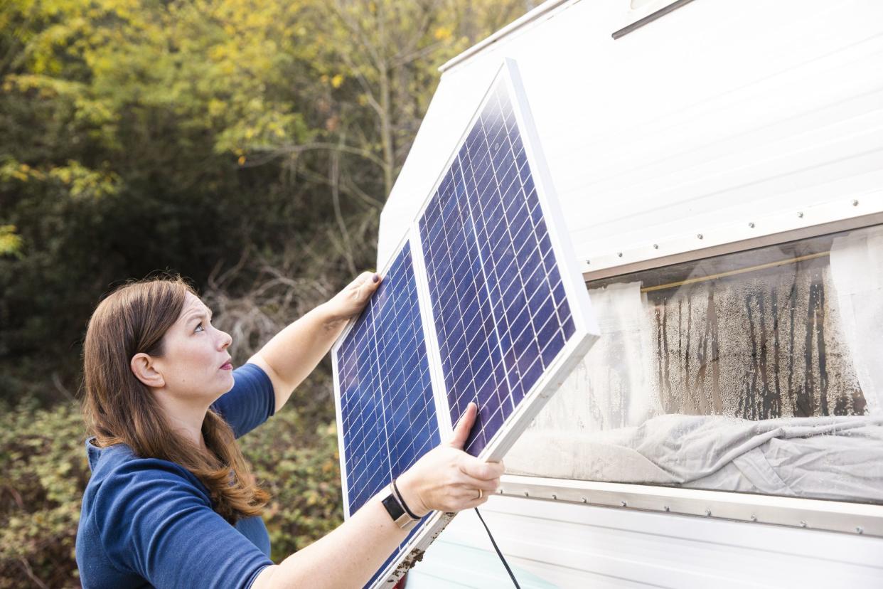 woman putting solar panel on rv roof