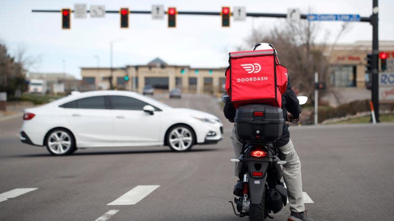 A DoorDash food delivery rider waits for the traffic light to change to head northbound on Chester Street at County Line Road in Lone Tree, Colorado.