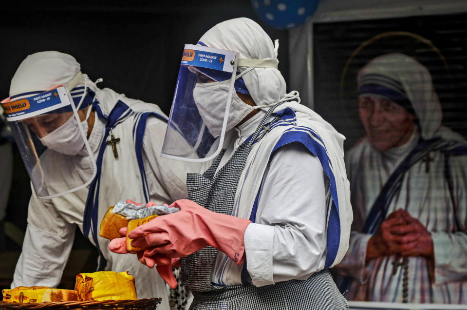 Nuns of the Missionaries of Charity, the order founded by Saint Teresa, wearing masks and face shields as precaution against the coronavirus distribute food to poor and homeless people in Kolkata, India, Wednesday, Aug. 26, 2020. Wednesday marked the birth anniversary of Nobel laureate Mother Teresa, a Catholic nun who spent 45-years serving the poor, the sick, the orphaned, and the dying. (AP Photo/Bikas Das)